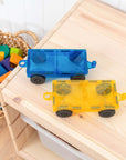 Rainbow Car Pack 2 pc: two magnetic motion car bases in blue and yellow with rubber wheels on a wooden table.