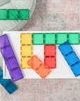 Rainbow Rectangle Pack 18 pc on a white table, showcasing colorful magnetic building tiles in vibrant hues.