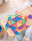 A child playing with colorful tile shapes from the Rainbow Shape Expansion Pack 36 pc, creating imaginative designs.