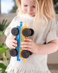 Child holding a toy train made of interlocking blocks in a home setting