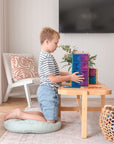 A child playing with the Rainbow Rectangle Pack 18 pc, stacking colorful magnetic tiles at a table.