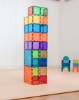 Colorful tower built with Rainbow Square Pack 42 pc tiles on a play mat.