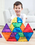 A joyful boy playing with colorful tiles from the Rainbow Shape Expansion Pack 36 pc, showcasing creative building.