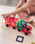 Child playing with the Rainbow Motion Pack 24 pc, building a colorful toy truck with wheels and figures.