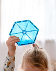 Child holding a blue tile from the Rainbow Geometry Pack 30 pc, showcasing creativity and geometric play.