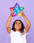 Child holding a colorful star-shaped tile from the Light Star Pack 28 pc against a purple background.