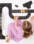 Child playing with the Creative Roads Pack 48 pc, building a racetrack with flexible road pieces.