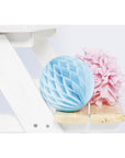 Blue honeycomb decoration and pink pom-pom next to a children’s picnic bench for outdoor fun.