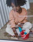 Child playing with a Cleaning Set featuring a bucket, spray-bottle, and squeegee, learning through imaginative play.