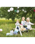 Children enjoying a picnic at the Nicki picnic bench surrounded by decorations and nature.