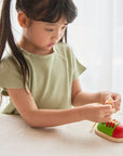 A child practices tying shoelaces with a colorful Lacing Shoe on a table.