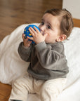 Child playing with a blue ball on a wooden floor