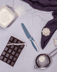 KiddiKutter Knife - Blueberry on a countertop with chocolate and baking ingredients, safe for kids to use.