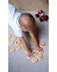 A child playing with wooden expression tokens from My Mood Memo on a soft rug.