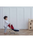 Child playing with a toy stroller, nurturing imagination with the PlanToys Feeding Set.