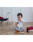 Child playing with the Feeding Set, nurturing a soft toy with a bottle and food container.