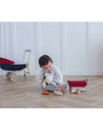 Child enjoying playtime with the PlanToys Feeding Set, nurturing and caring for a soft toy.