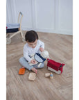 Child enjoying the PlanToys Feeding Set, nurturing playtime with dolls and toys.