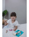 Child playing with PlanToys Dentist Set, exploring dental care with wooden tools and teeth.