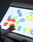 Child exploring numbers on Tickit A3 Rectangular Light Panel, enhancing learning through light and color.