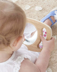 A child exploring reflections with the Tickit Easy Hold Convex Concave Mirror on a soft rug.
