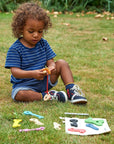 Child playing with Rainbow Wooden Keys on grass, engaging in hands-on play and learning.