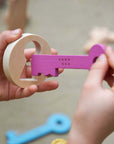 Child playing with a pink key from the Rainbow Wooden Keys set, engaging in hands-on play.