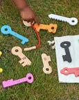Child playing with Rainbow Wooden Keys on grass, showcasing colorful, smooth, and educational wooden play keys.