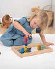 Child playing with Tickit Gem Cubes, stacking colorful transparent gem cubes on a wooden tray.