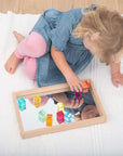 Child using Tickit Gem Cubes to build and play with reflections in a mirror on a sensory mat.