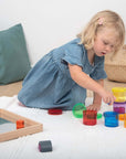 Child playing with Tickit Gem Cubes on a bright rug, building and sorting colorful transparent gems.