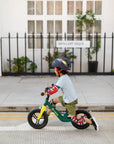 Child riding the Micro Balance Bike Peacock Green on the street, showcasing its lightweight design and fun colors.