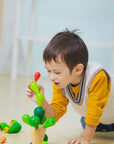 Child playing with PlanToys Balancing Cactus game, stacking colorful wooden branches carefully.