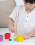 Young child enjoying the Beehives activity with colorful wooden blocks and tweezers.
