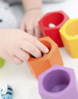 Child's hand engaged in a matching activity with colorful Beehives set, promoting fine motor skills and color recognition.