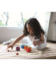 Child engaging with PlanToys Beehives set, matching colorful bees to hives for fine motor skills.