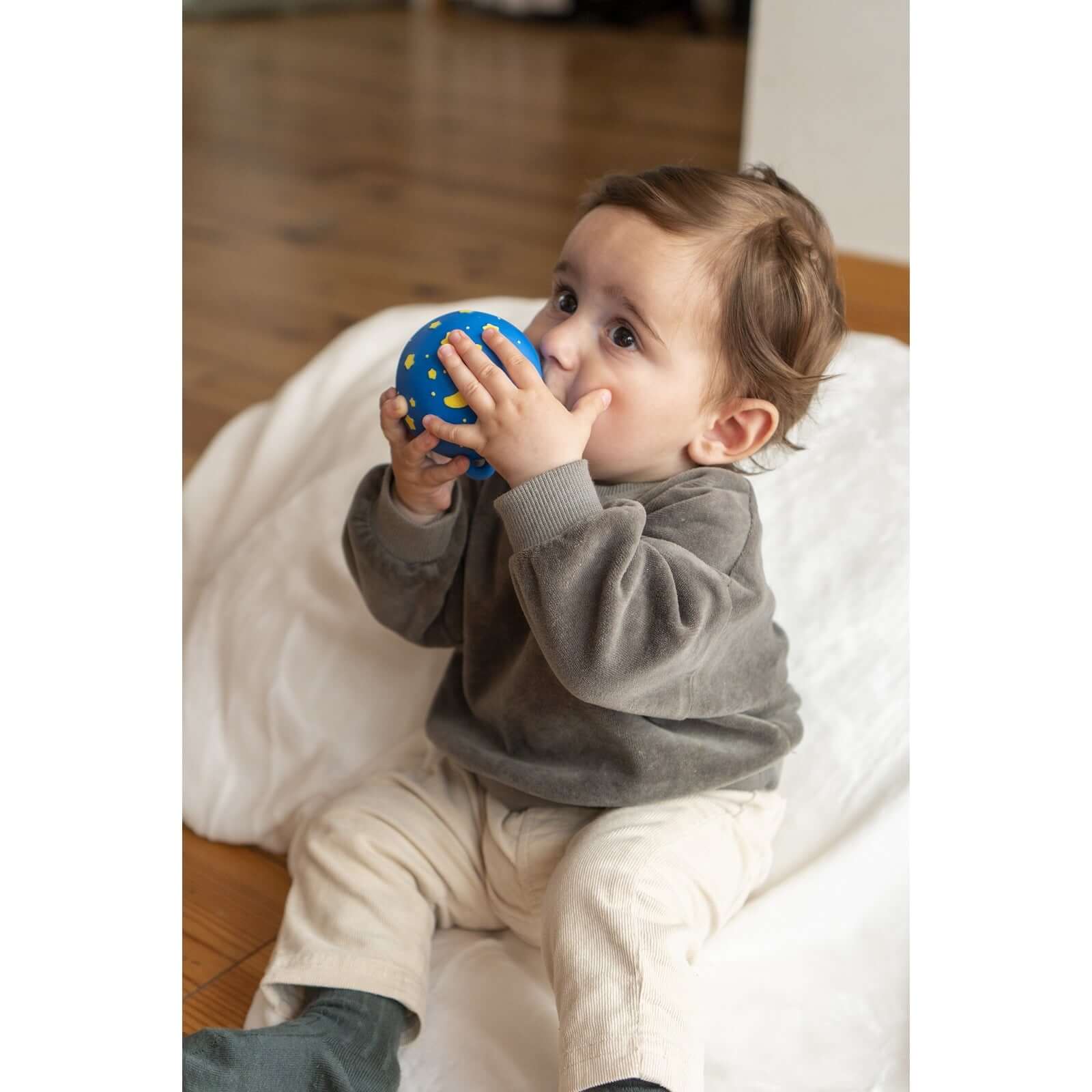A child exploring a blue sensory ball, embodying the joy of The Sensory Seeker collection.