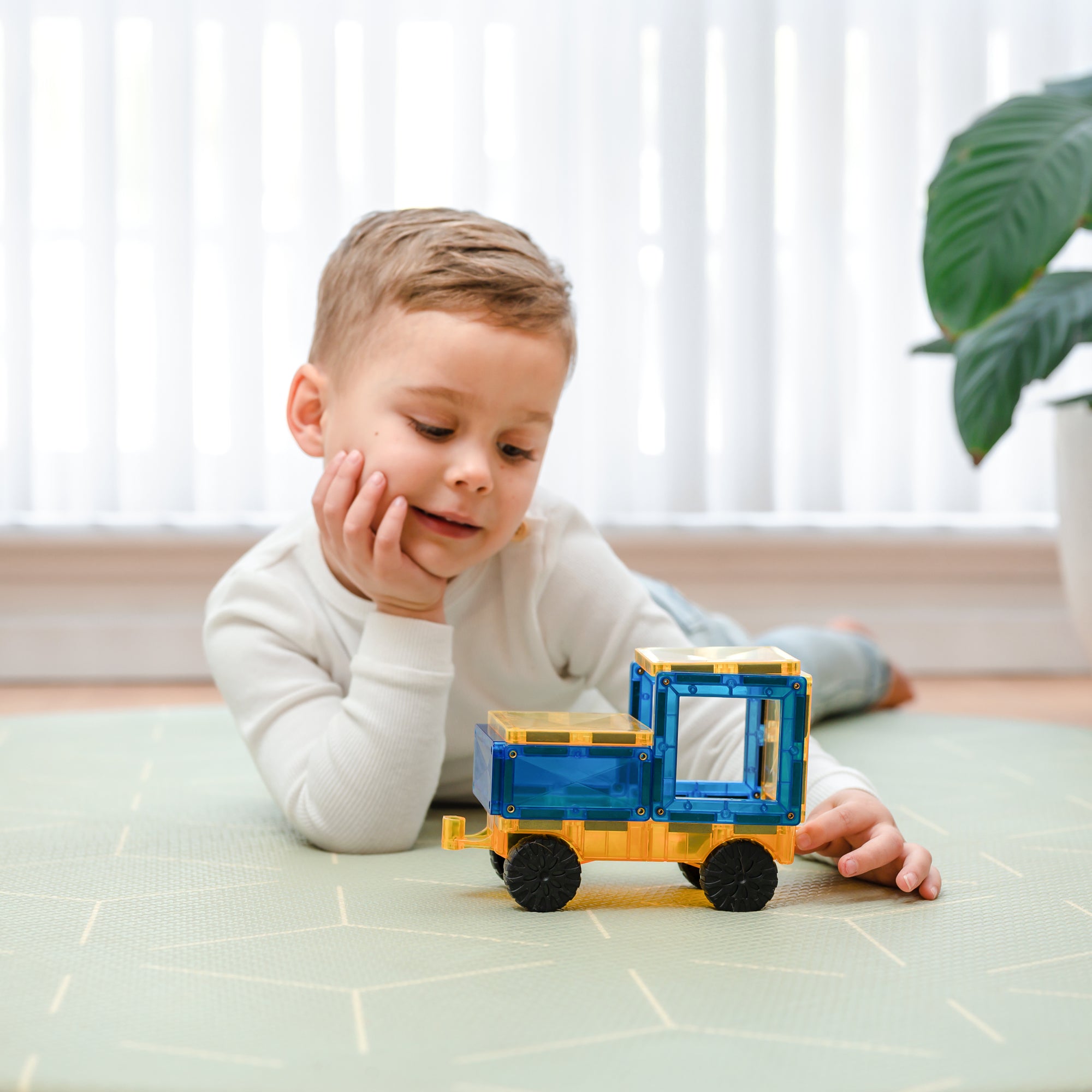 Child playing with a toy truck on a tiled floor