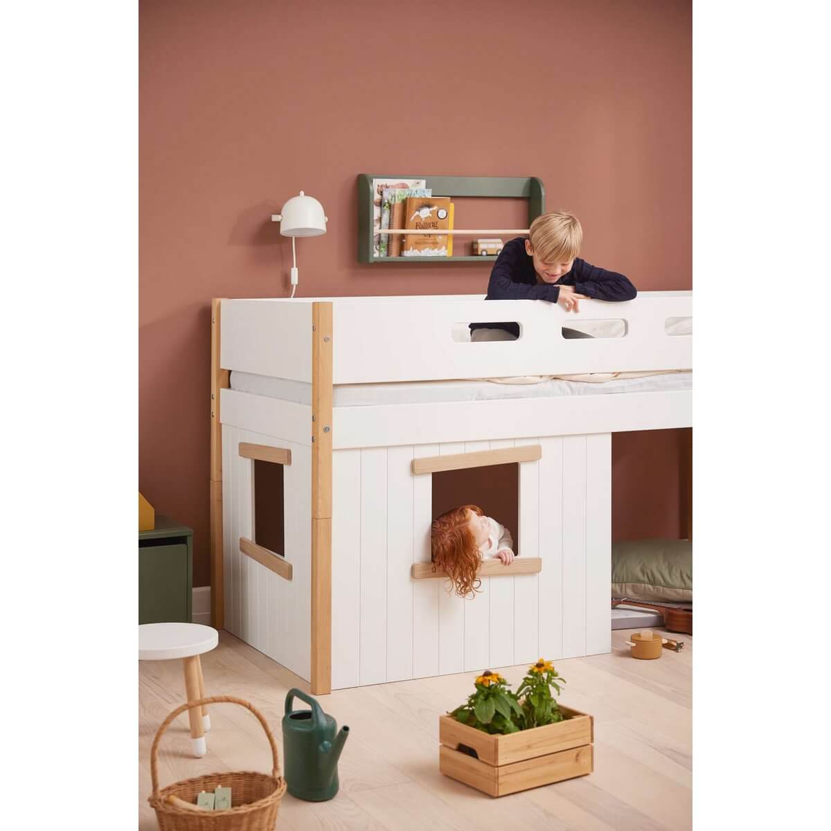 High bed with treehouse design, safety rail, and child playing, ideal for imaginative indoor play and cozy sleep.