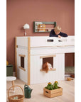 High bed with treehouse design, safety rail, and child playing, ideal for imaginative indoor play and cozy sleep.