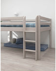 High bed with safety rail and ladder, white frame, featuring a cozy area underneath for play or storage.