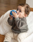 Child playing with a blue ball on a wooden floor