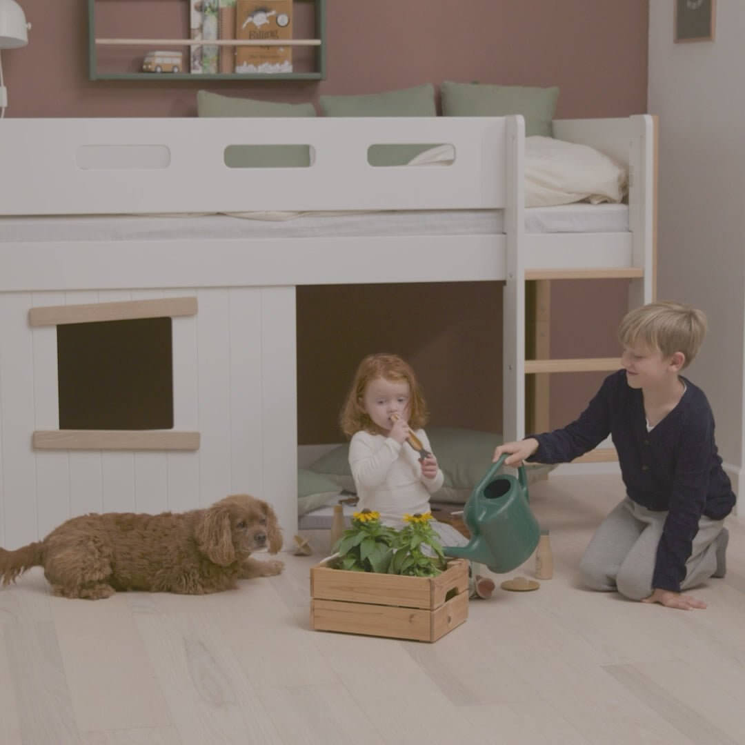 Children playing under a high bed with treehouse design, featuring a cozy hideaway and a dog nearby.