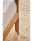 Close-up of the oak frame and legs of the FLEXA Nova Junior Bed on wooden flooring.