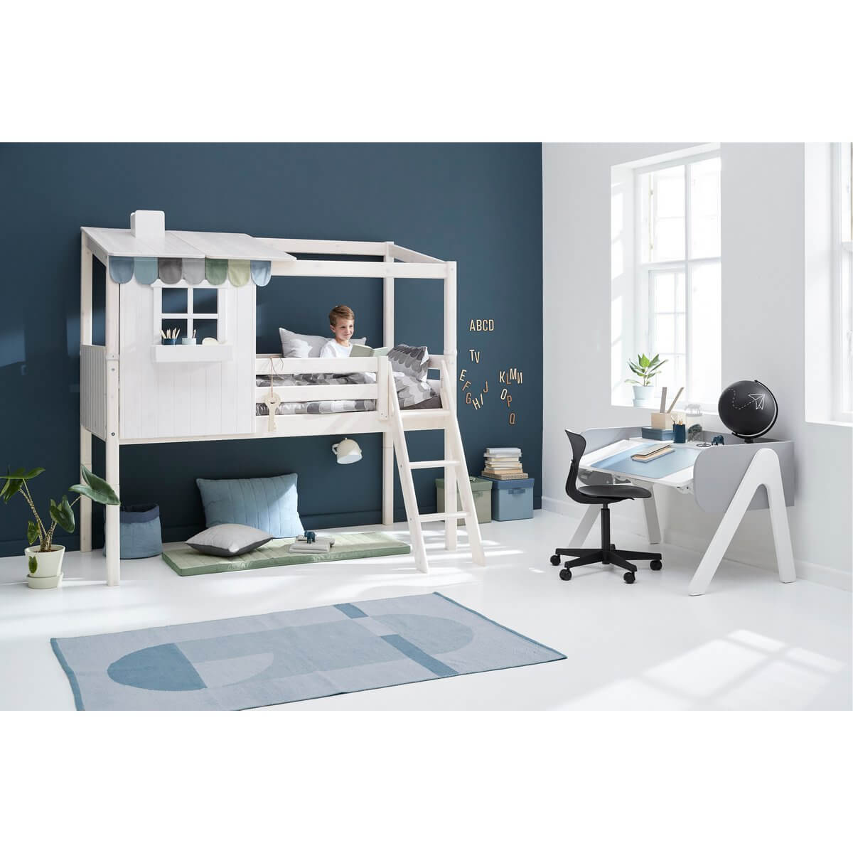 Child relaxing in a high bed with house design, featuring a ladder and play area in a cozy room with modern decor.