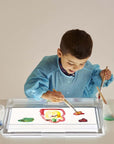 Child painting on the Tickit A3 Rectangular Light Panel, exploring colors and creativity.