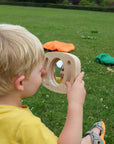 Child exploring reflections with Tickit Easy Hold Convex Concave Mirror on a sunny day outdoors.